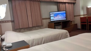 Habitación de hotel con dos camas, un televisor sobre un mueble bajo, un escritorio con teléfono y una silla.