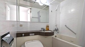 Un baño con bañera, lavabo con espejo y retrete.