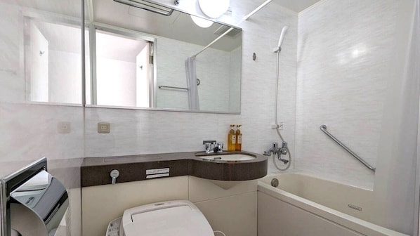 A bathroom with a bathtub, a sink with a mirror above it, and a toilet. - Hotel Alpha-One Yokohama Kannai (Yokohama)