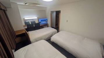 A hotel room with two single beds, a desk with a computer, and a wardrobe.