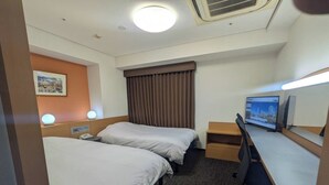 Habitación de hotel con dos camas, un escritorio, una computadora y un televisor.