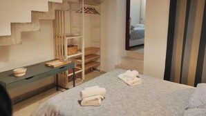 Une chambre à coucher comprenant un lit, une table de chevet, une armoire suspendue et un escalier menant à une autre pièce.