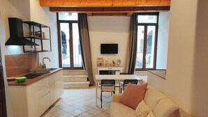 Un espace de vie compact comprenant une kitchenette, un coin repas et un espace détente.
