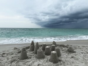 Una playa con esculturas de arena y el océano bajo un cielo nublado.