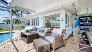 A covered outdoor seating area with wicker furniture, a pool, and a view of the outdoors. - Waterfront 3BR – Pool, Dock, Kayaks & Beach (Englewood)