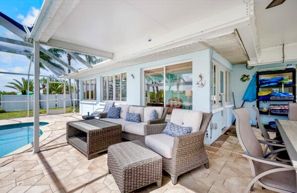 Un espacio de estar al aire libre cubierto con muebles de mimbre, una piscina y vistas al exterior.