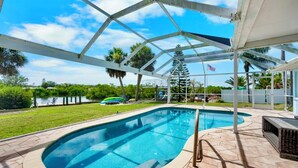 A covered swimming pool with a view of a lake and palm trees. - Waterfront 3BR – Pool, Dock, Kayaks & Beach (Englewood)