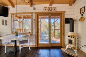 A wooden interior with a dining table, chairs, a fireplace, and large windows. - Tranquil Cabin on Sleeping Child Creek (Hamilton)