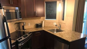 A compact kitchen with a microwave, stove, oven, and sink.