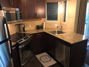 A compact kitchen with a microwave, stove, oven, and sink.