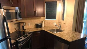 A compact kitchen with a microwave, stove, oven, and sink.