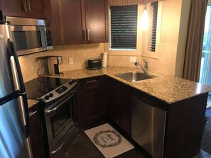 A compact kitchen with a microwave, stove, oven, and sink.