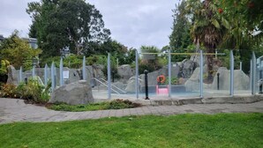 A glass-enclosed outdoor area with a pool, surrounded by rocks and greenery. - Estuary Escape - 1BDRM - Full Kitchen (Nanoose Bay)