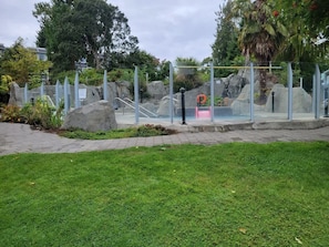 A glass-enclosed outdoor area with a pool, surrounded by rocks and greenery.
