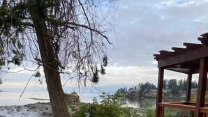 A wooden deck with a table and chairs, a pergola, and a view of a body of water. - Estuary Escape - 1BDRM - Full Kitchen (Nanoose Bay)