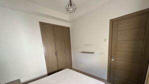 A bedroom with a bed, wooden wardrobe, and a shelf. - Luxury apartment  (Ariana)