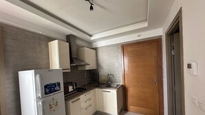A compact kitchen with a refrigerator, stove, sink, and cabinets. - Luxury apartment  (Ariana)