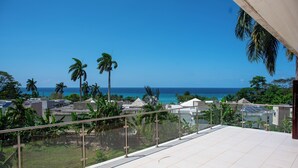 Varanda com vista desobstruída para o oceano e palmeiras.