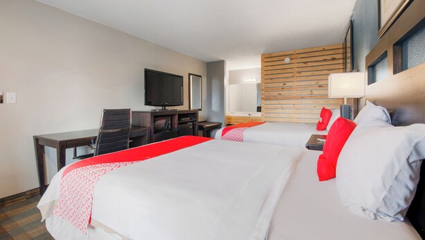 A hotel room with two beds, a desk, a television, and a wooden wall panel. - Capital O 3Y Motel Mount Vernon Renfro Valley (Mount Vernon)