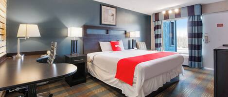 A hotel room with a bed, desk, and two bedside lamps.
