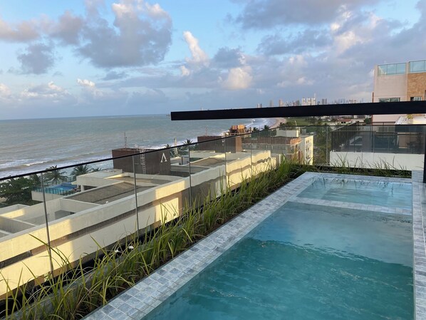 Une piscine sur le toit offrant une vue sur l’océan et le paysage urbain.