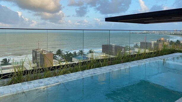 An infinity pool with a view of the ocean and cityscape. - Bela Hospedagem - Neo Duos 104 (Cabedelo)