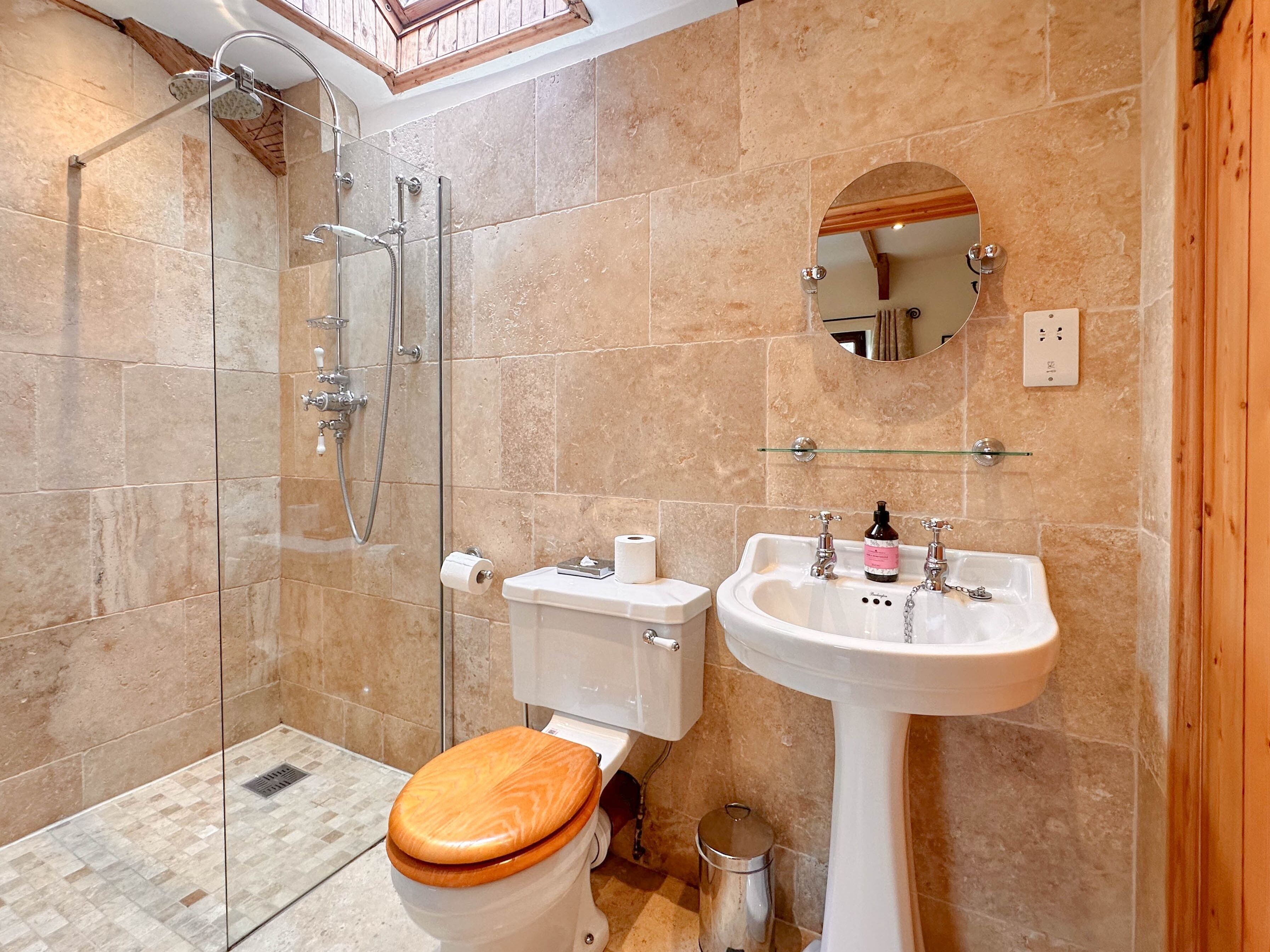 Un bagno con doccia, WC, lavandino e specchio.