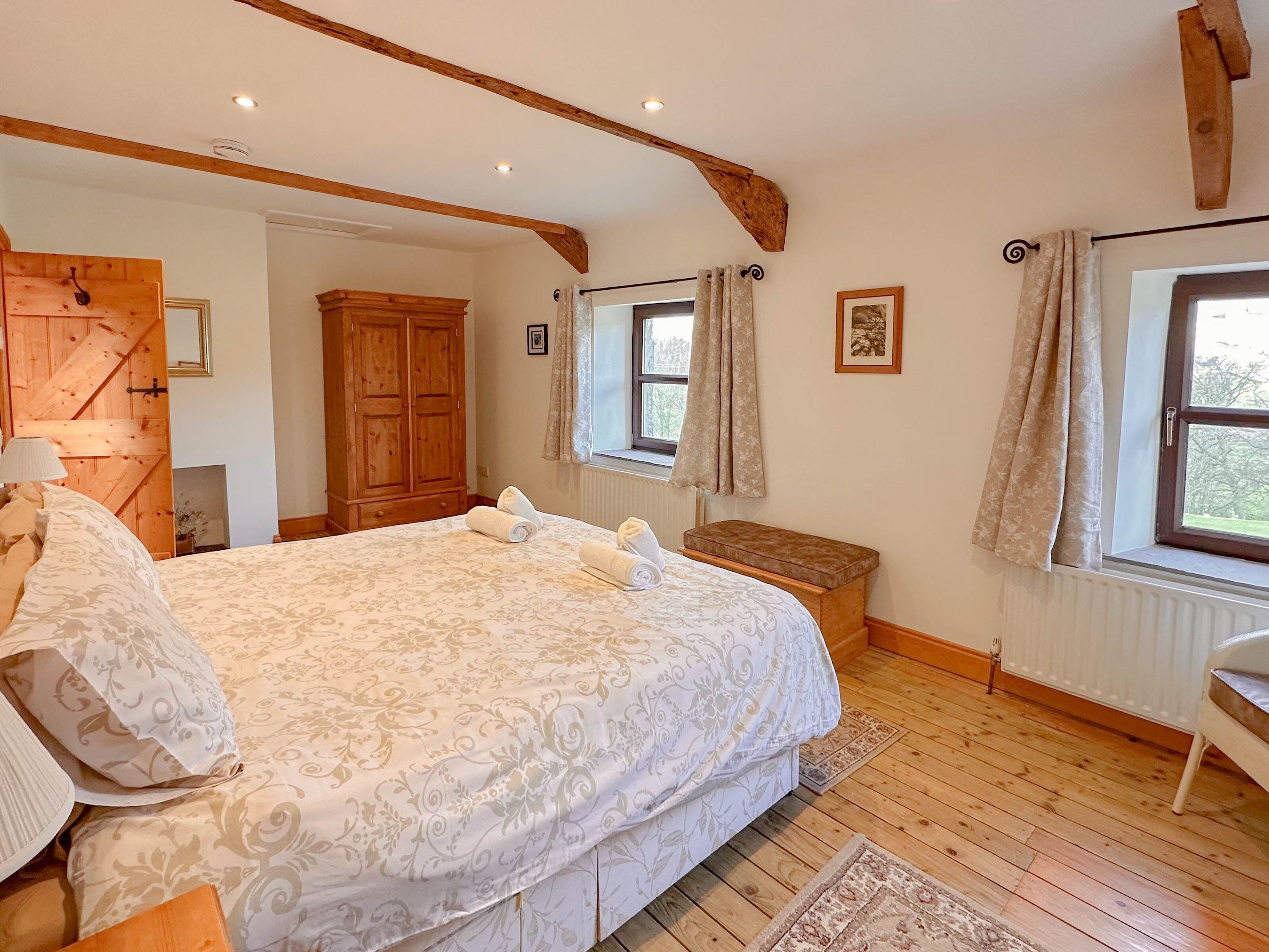 Une chambre à coucher avec un grand lit, une armoire en bois et une fenêtre avec des rideaux.