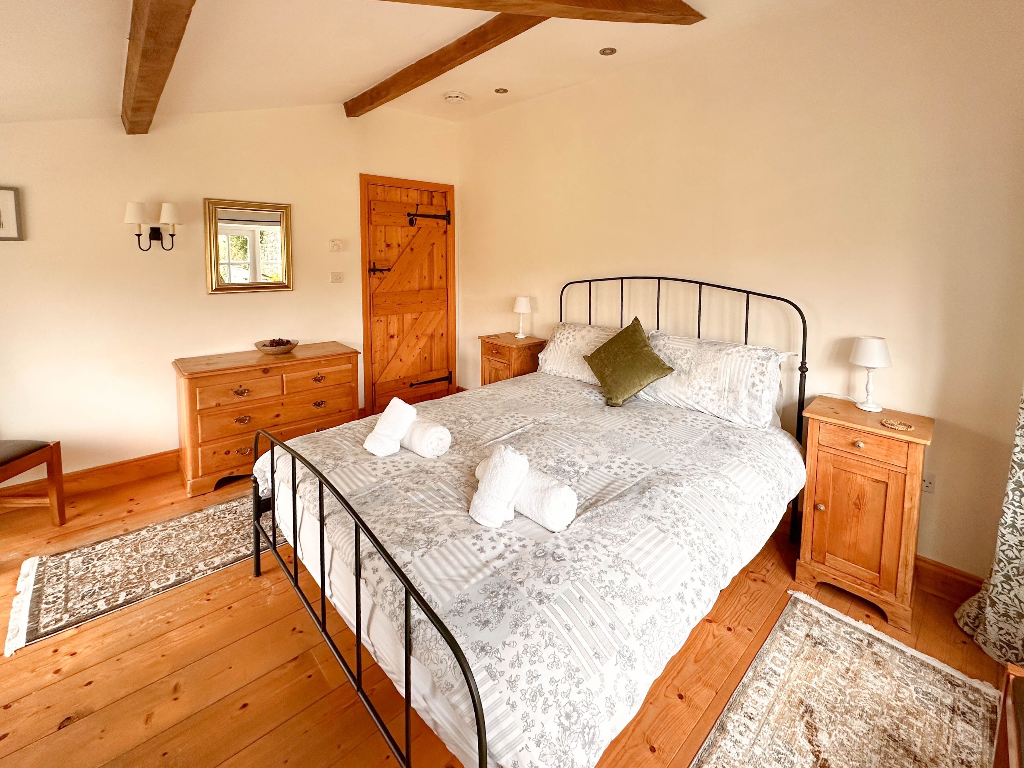 A bedroom with a metal bed frame, wooden dresser, and nightstands.