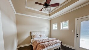 Quarto com cama, ventilador de teto e porta.
