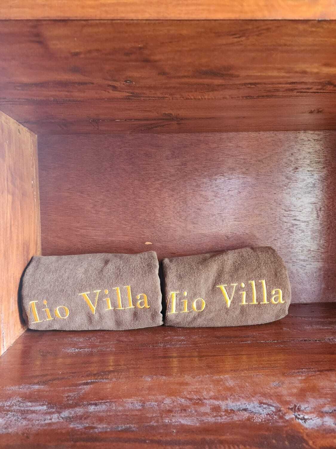 Two towels with embroidered text placed on a wooden shelf.