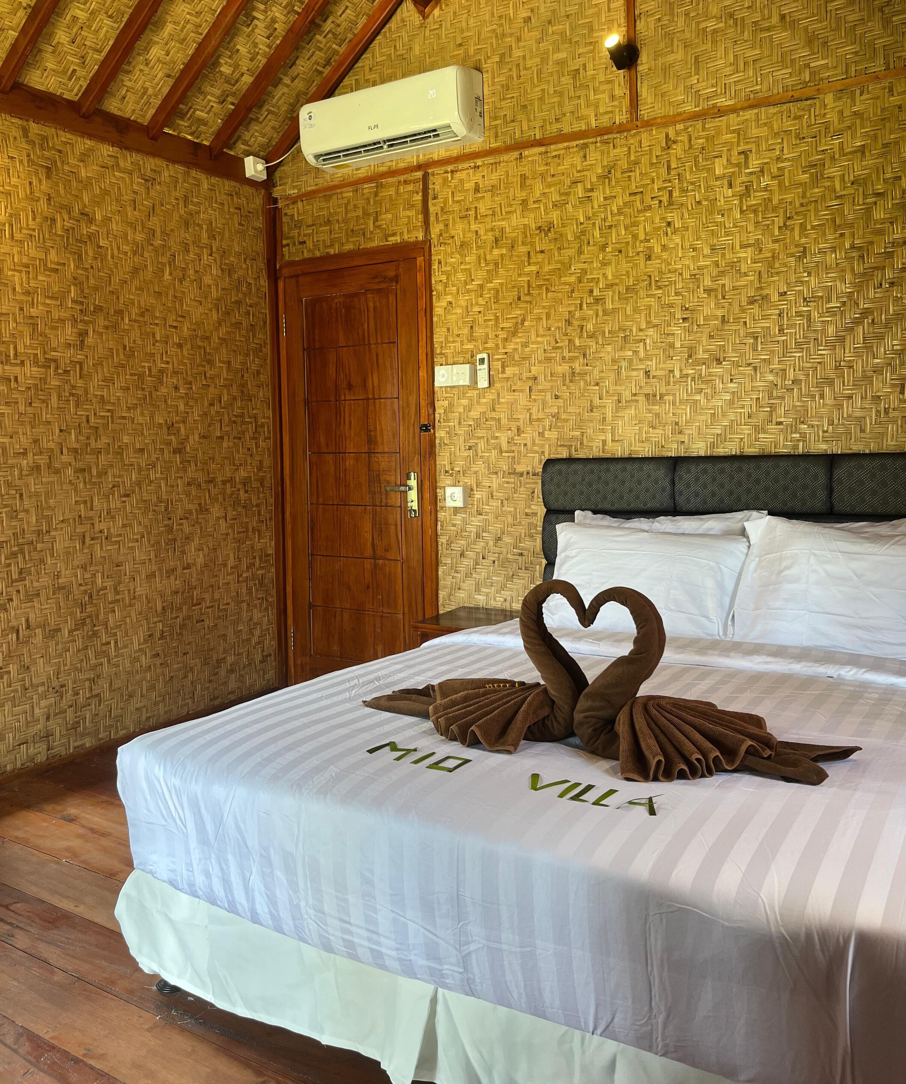 A hotel room with a bed, a wooden door, and a woven wall pattern.