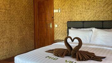 A hotel room with a bed, a wooden door, and a woven wall pattern.