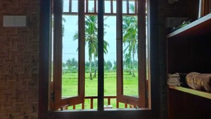 A wooden door with a view of a green field and palm trees. - Mio Villa Tomang Omang Lombok (Selong Belanak)