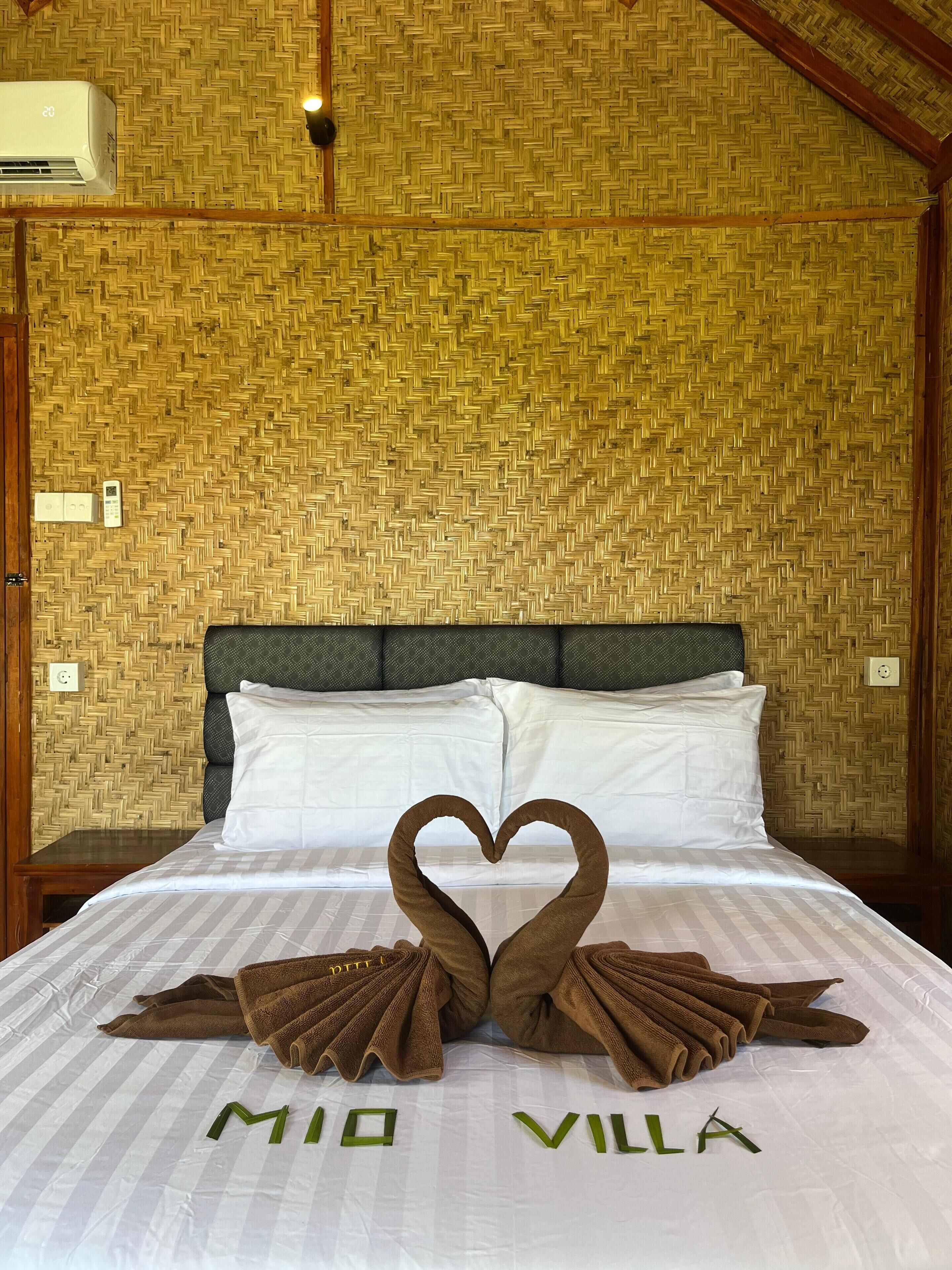 Een bed met een handdoekarrangement in de vorm van een hart en de tekst 'MIO VILLA' op de plaid.