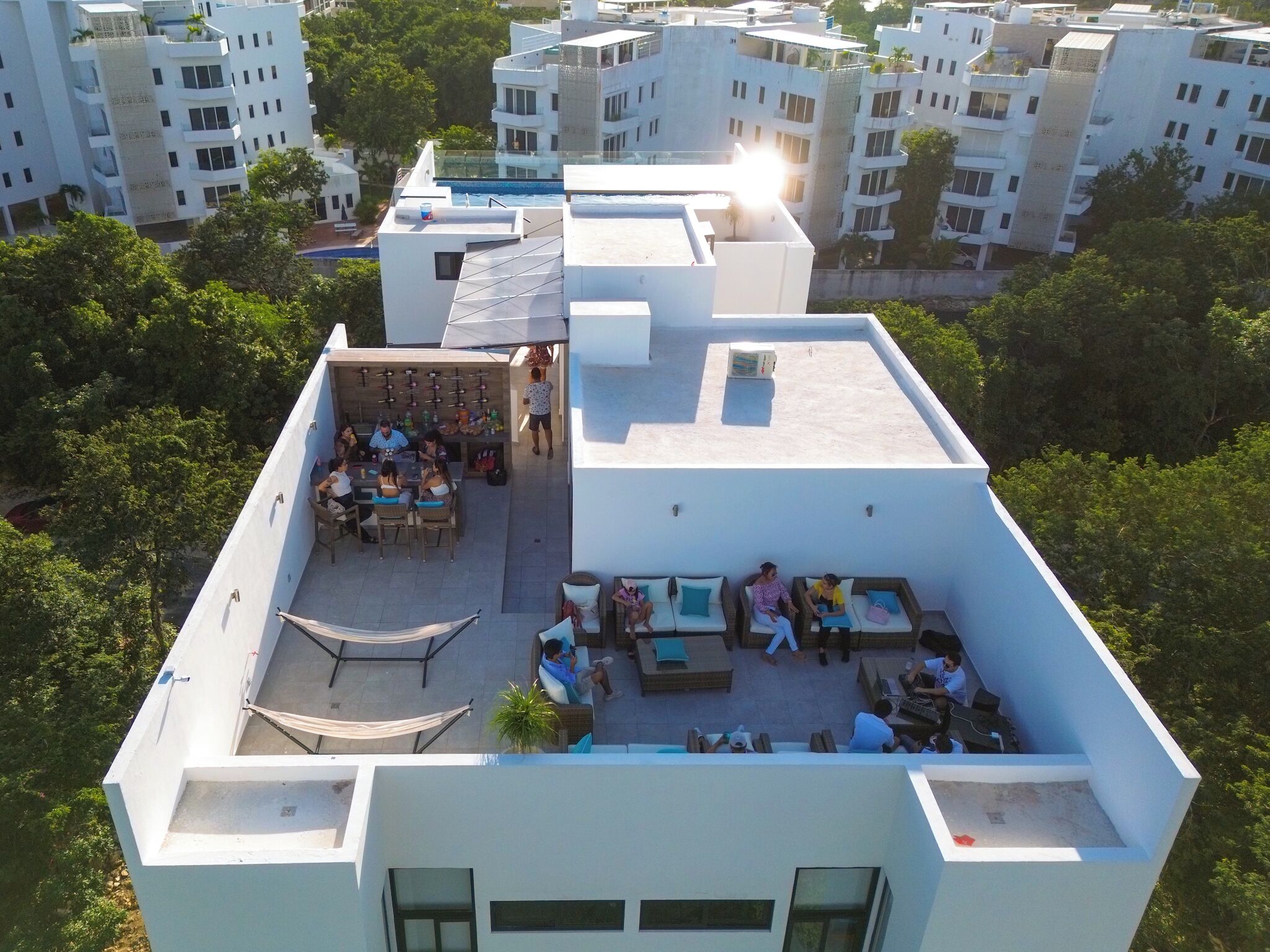 Vue aérienne d’une terrasse sur le toit, avec des espaces de détente en plein air, une piscine et une végétation luxuriante tout autour.