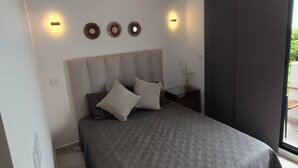 A modern bedroom with a large bed, a wall-mounted air conditioner, and decorative wall sconces. - Modern vacation apartment with gym, jacuzzi, rooftop pool and sauna. (Playa del Carmen)