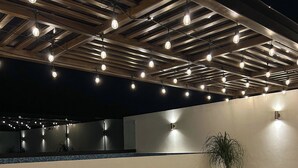 An outdoor lounge area with multiple sun loungers, a potted plant, and a pool in the background. - Modern vacation apartment with gym, jacuzzi, rooftop pool and sauna. (Playa del Carmen)