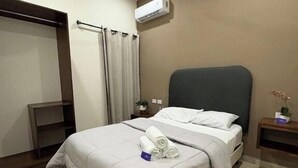 A hotel room with a bed, a ceiling fan, an air conditioning unit, a small bedside table with a plant, and a wardrobe. - Hortensias Hotel and Suites (Tapachula)