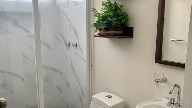 A bathroom with a toilet, sink, and a shower with a glass door. - Hortensias Hotel and Suites (Tapachula)