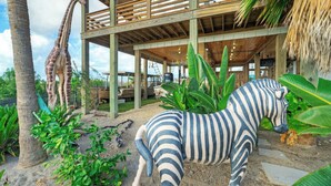 A zebra statue, a giraffe statue, and a wooden structure with a thatched roof. - Fish Camp by Avantstay Unique Escape, Pool + Views! (Port Aransas)