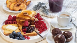 A breakfast setting with toast, berries, muffins, and a cup of coffee.