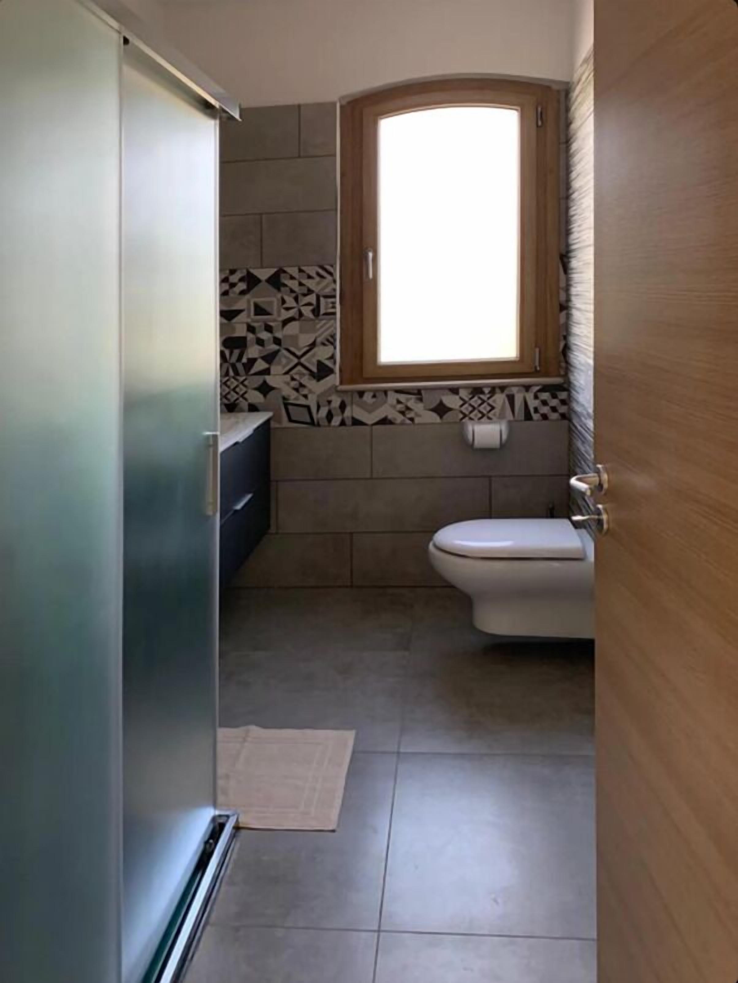 A small bathroom with a toilet, a sink, and a window.