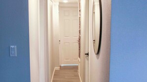 A narrow hallway with wooden flooring, white walls, and a door at the end. - Welcome to The Cozy Cove, Your Lakeside Retreat (Havasu Lake)
