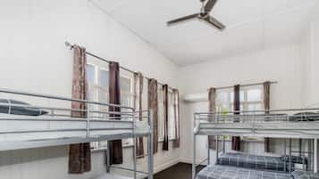 Un dormitorio con literas, ventilador de techo y cortinas en las ventanas.