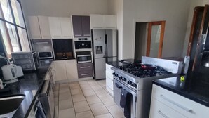 Eine moderne Küche mit weißen Schränken, einem Gasherd, einem Backofen, einer Mikrowelle und einem Kühlschrank.