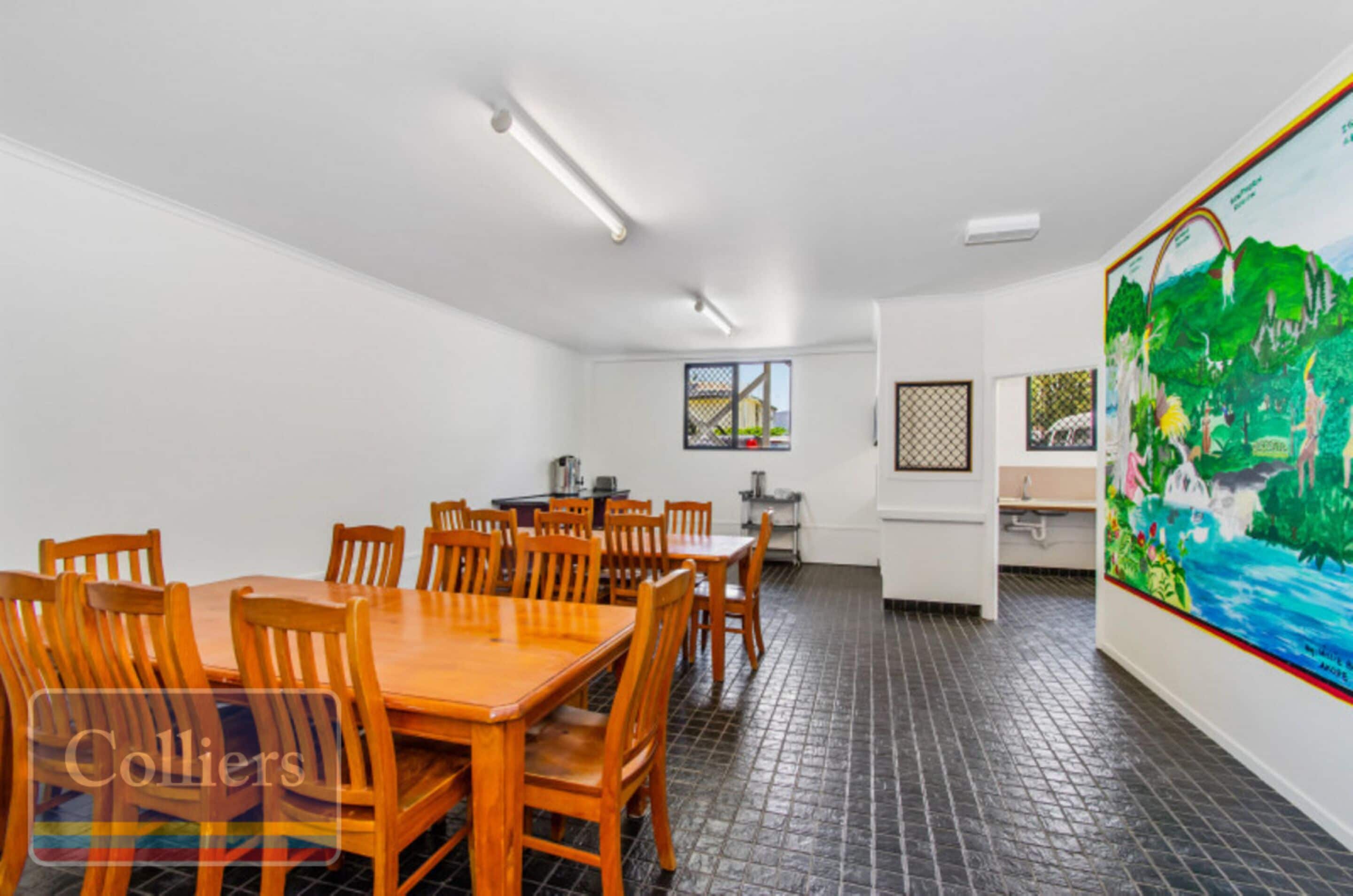 A conference room with a long table and chairs, a window with a view, and a large painting on the wall.