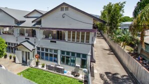 Ein zweistöckiges Haus mit Balkon, Veranda und umzäunter Garten.