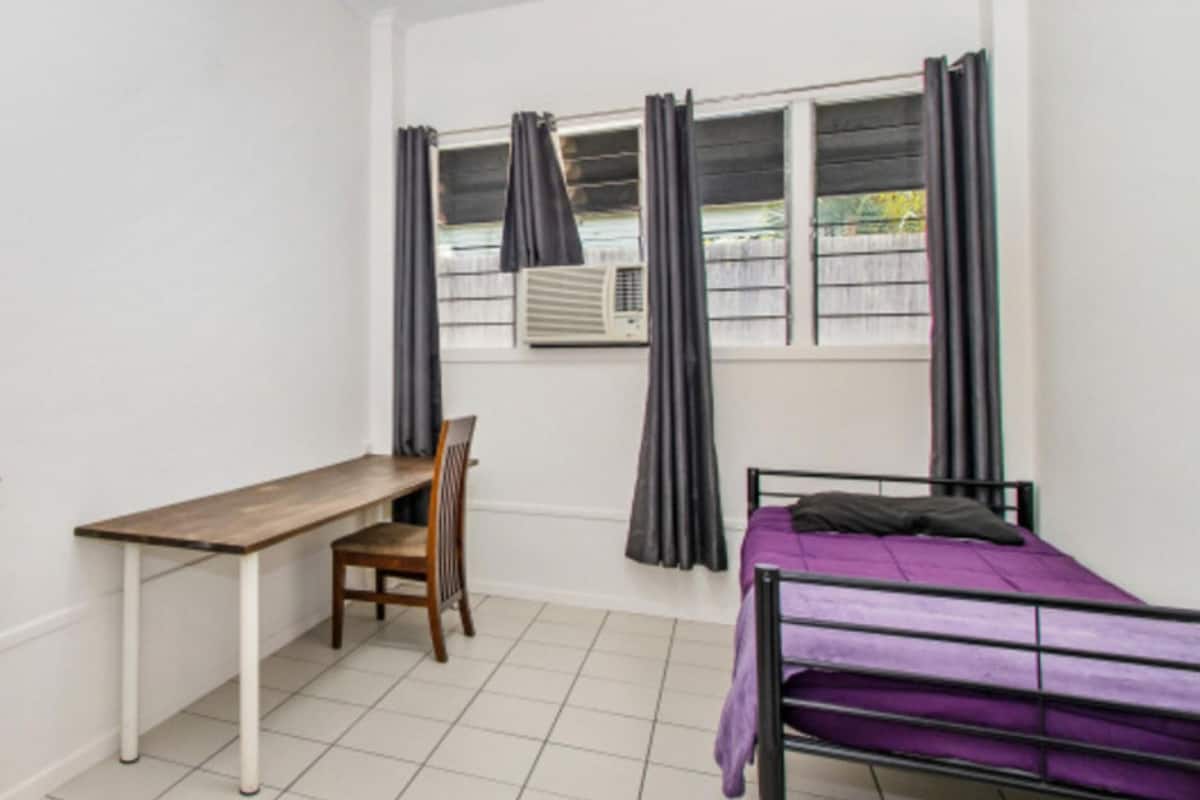 Une petite pièce propre, avec un lit, un bureau et une chaise.