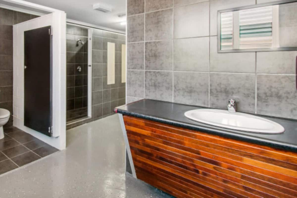 Une salle de bain moderne avec un meuble-lavabo en bois, un grand miroir et un espace douche.